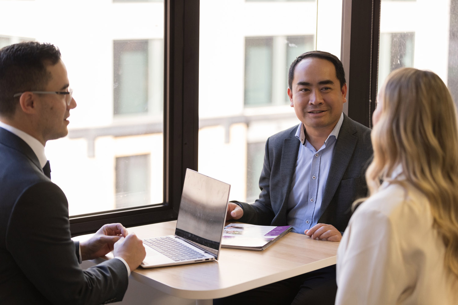 Three professionals discussing ideas at a workspace.