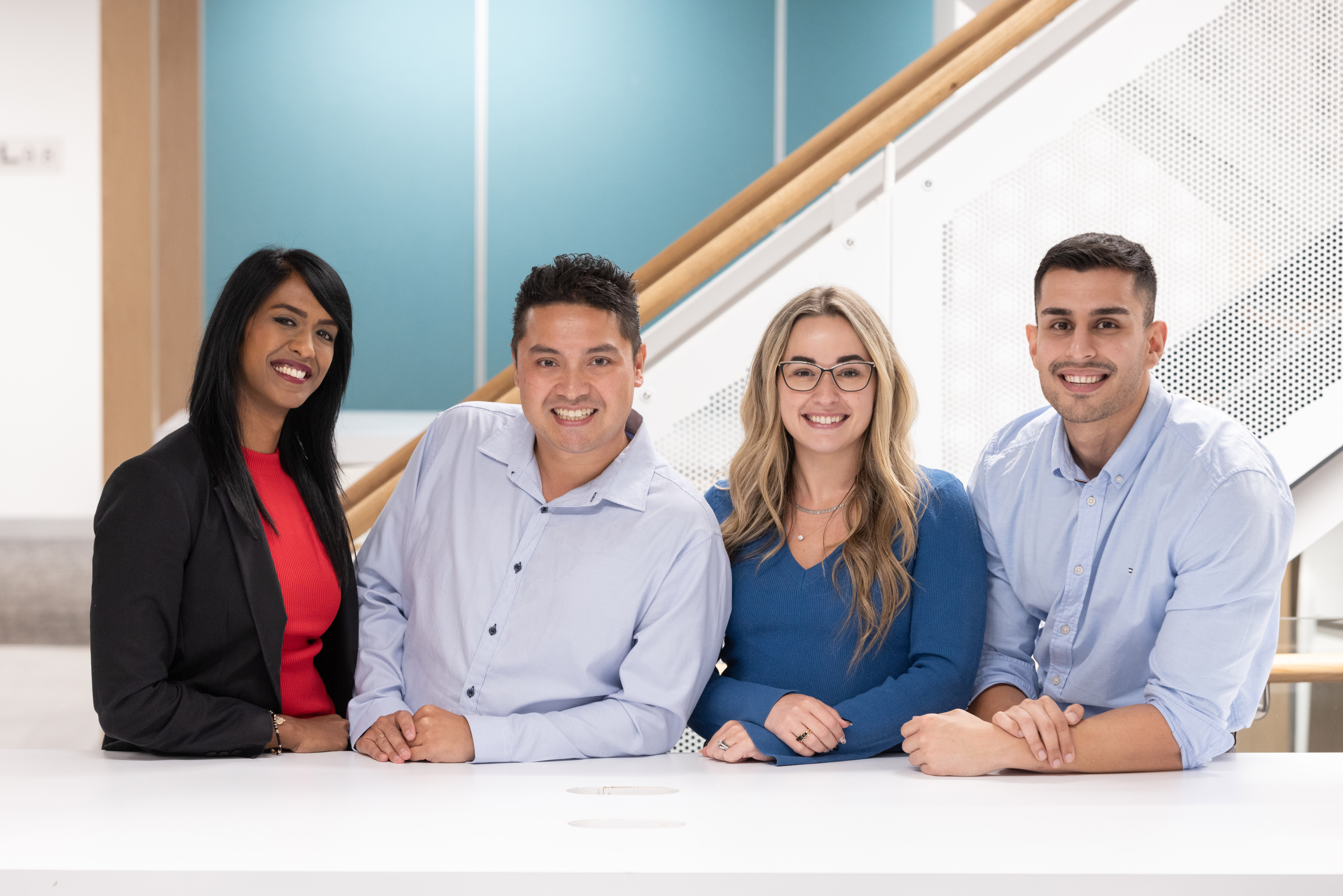Diverse group of four smiling professionals indoors.