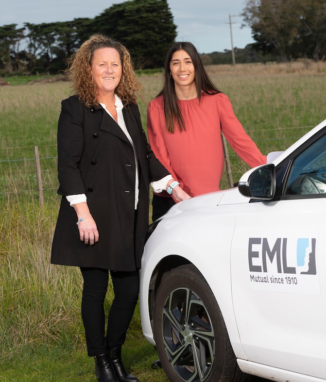 Two women standing beside a company-branded car.