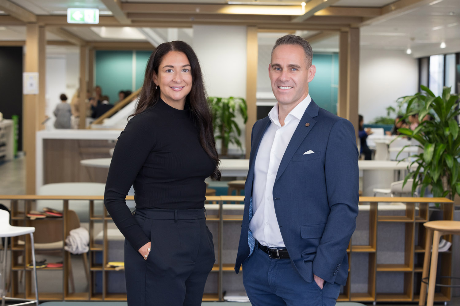 Two professionals posing in a modern office space.