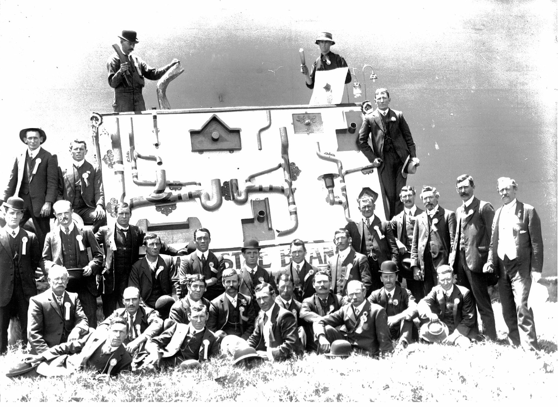 Group portrait of men with machinery backdrop.