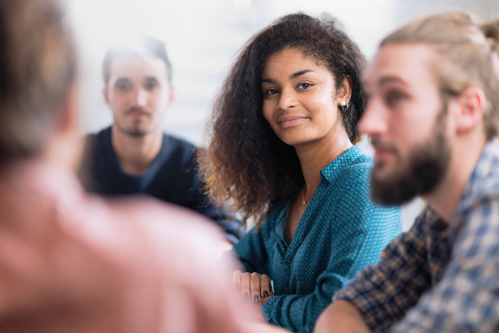 Diverse group meeting with focus on smiling woman.