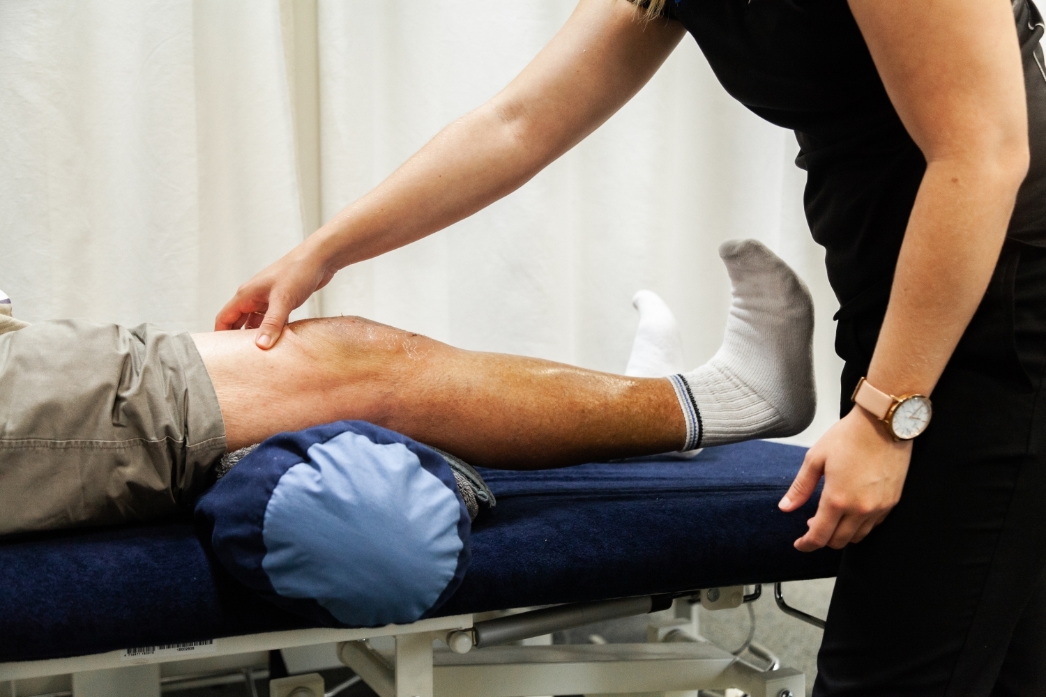 Physiotherapist examining patient's knee on treatment table.