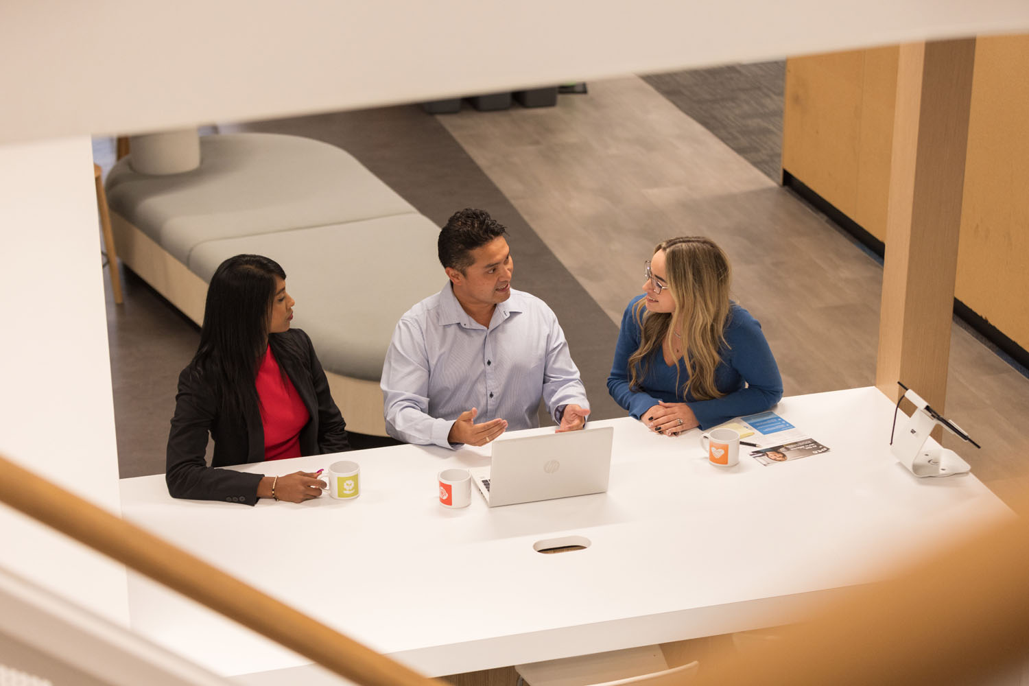 Three colleagues discussing at a modern office table.