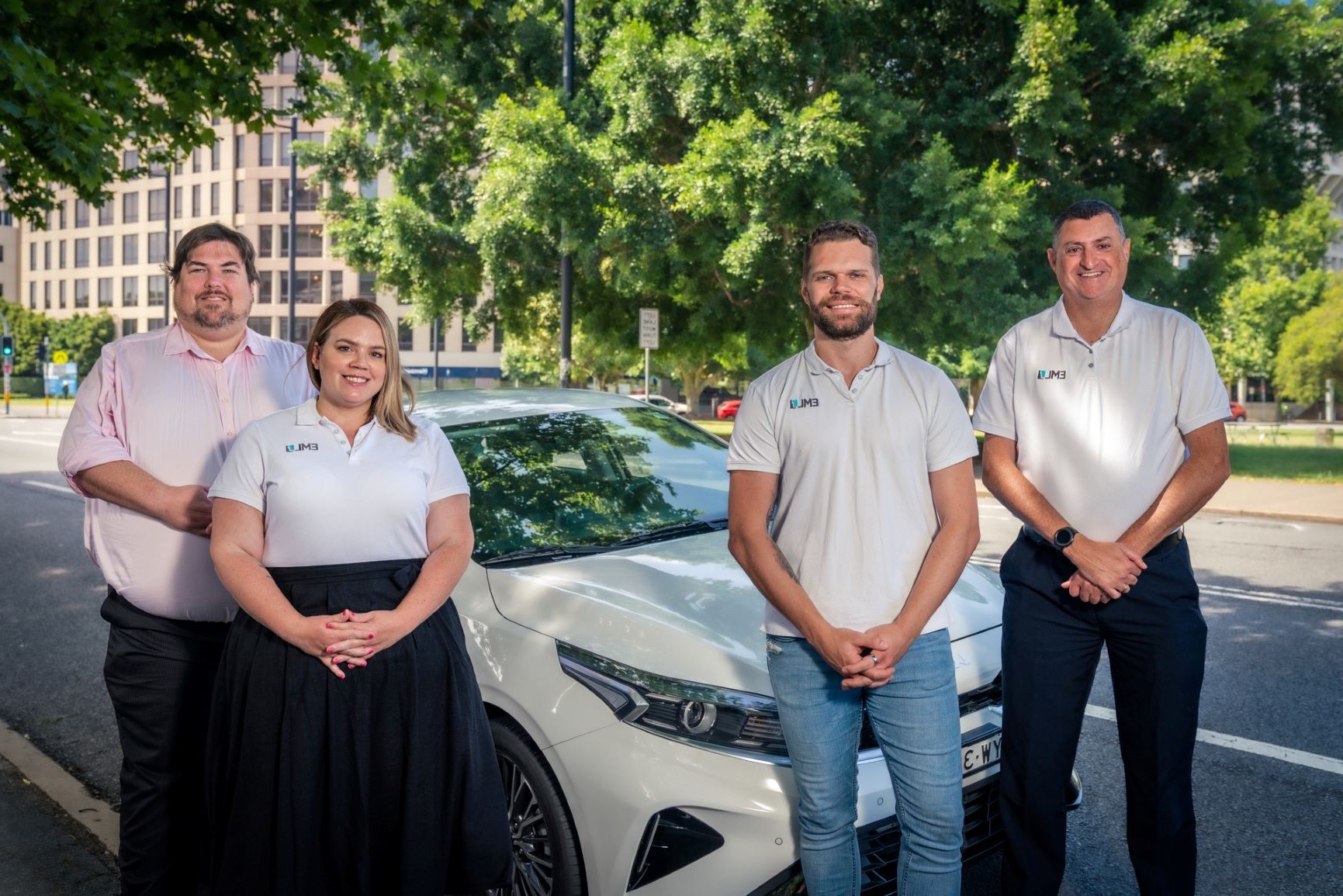 Four people standing in front of a car.