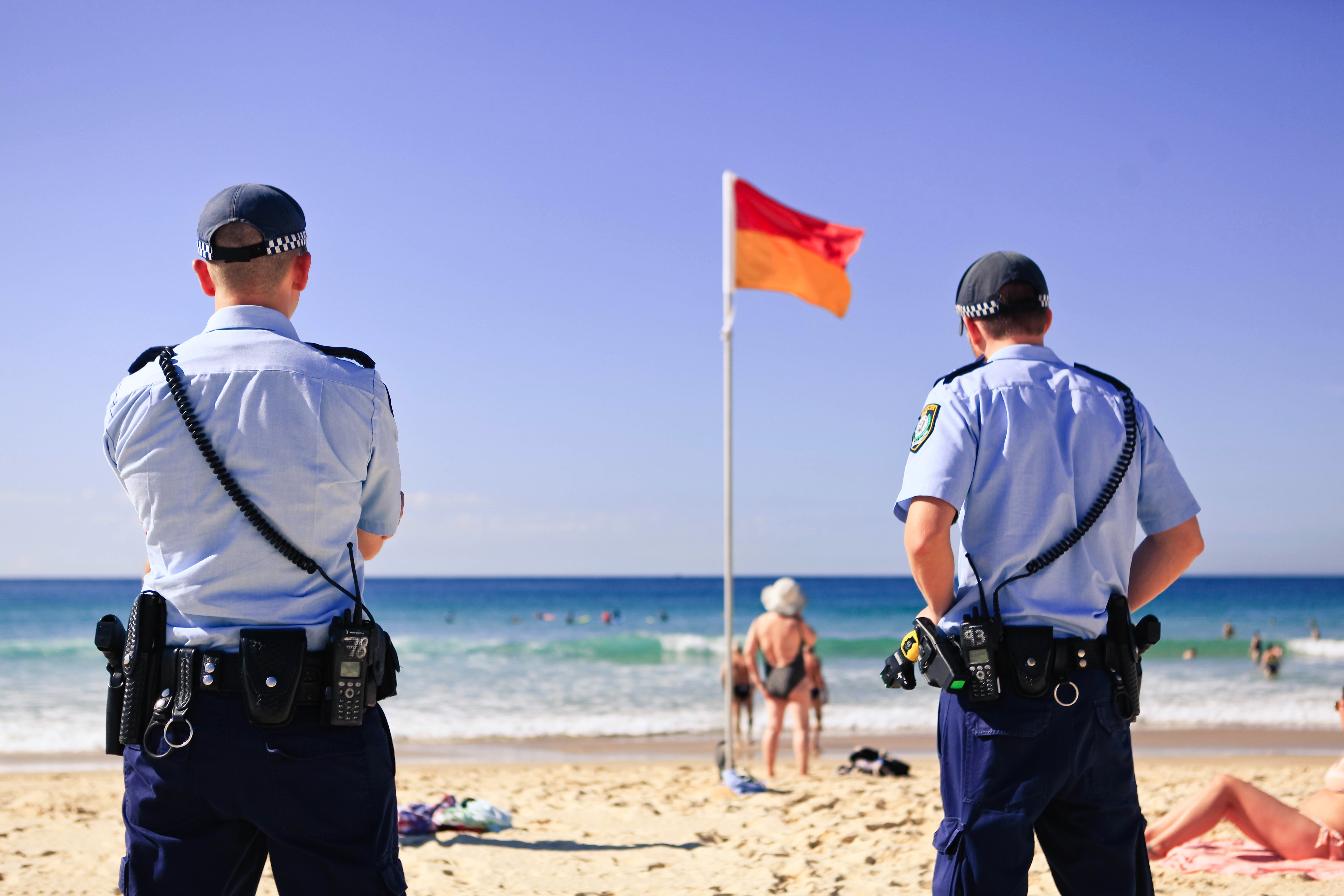 Police officers monitoring a crowded beach scene.