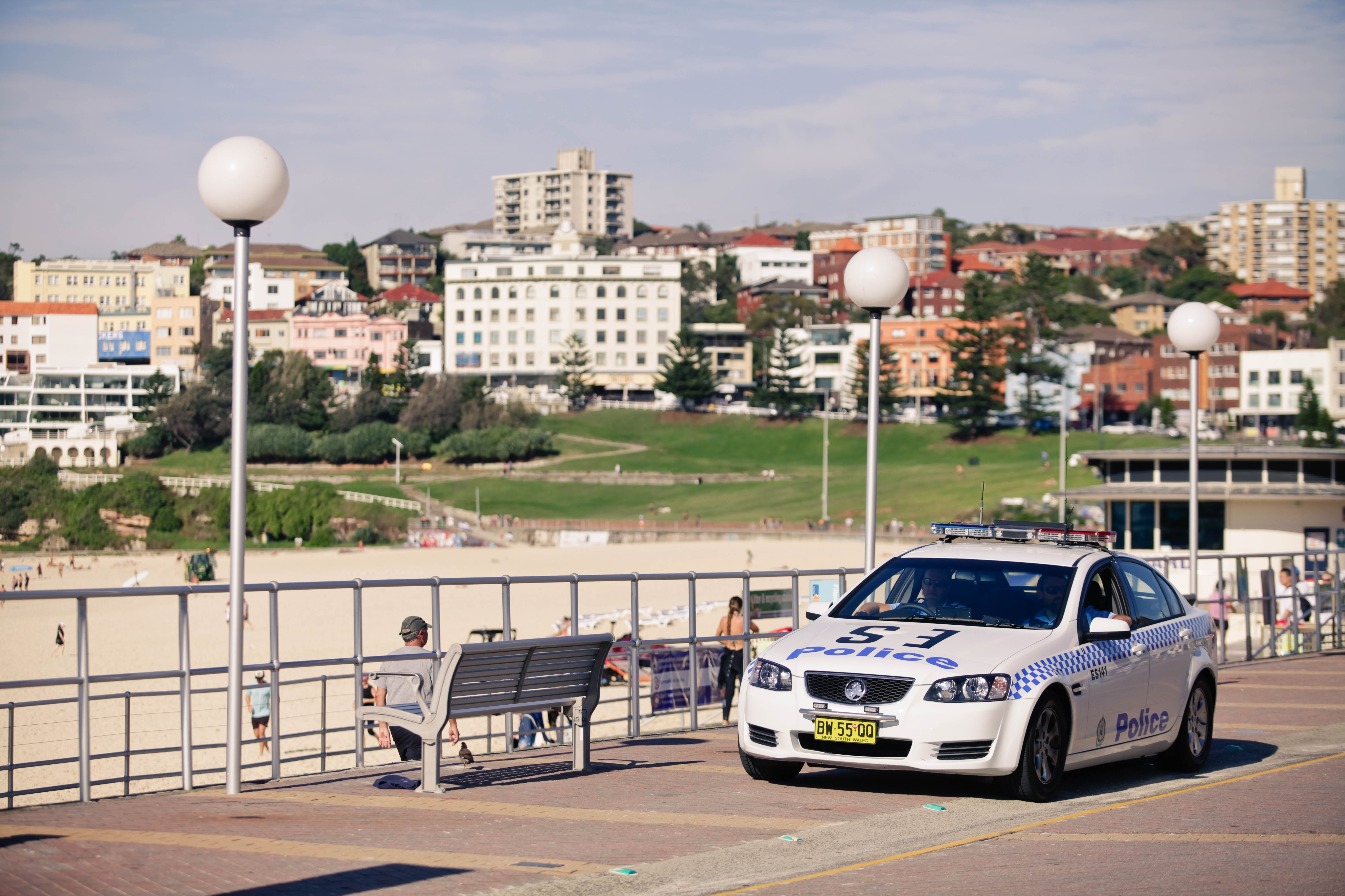 Police car parked near beach and promenade.