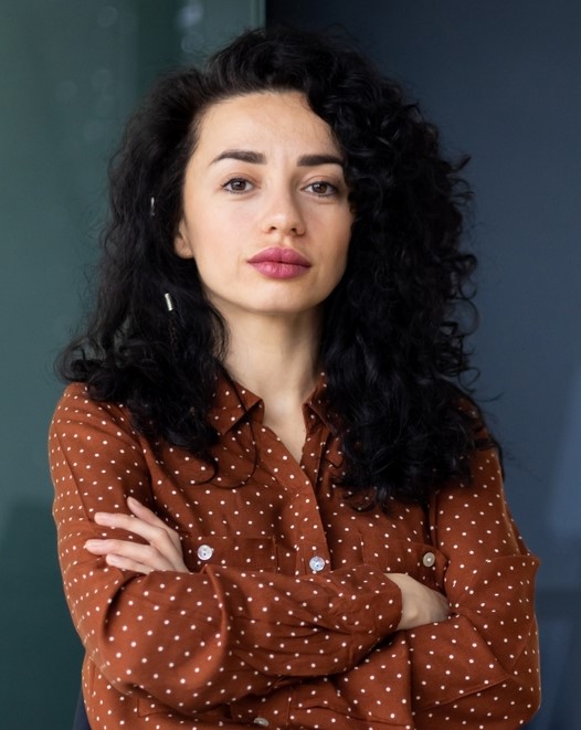 Confident woman with curly hair and folded arms.