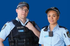 Two police officers standing together against blue background.